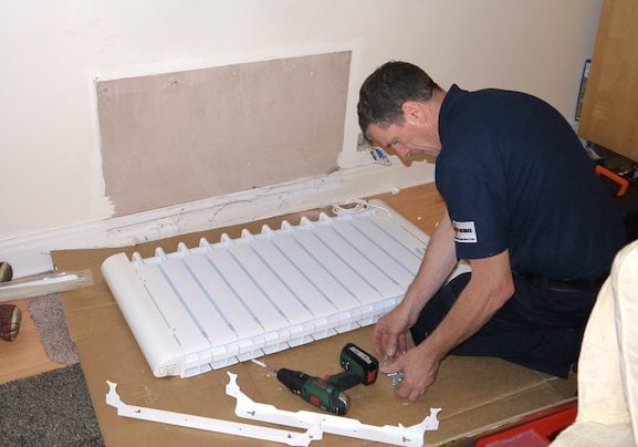 Electric heater installer in London measuring and aligning heater brackets